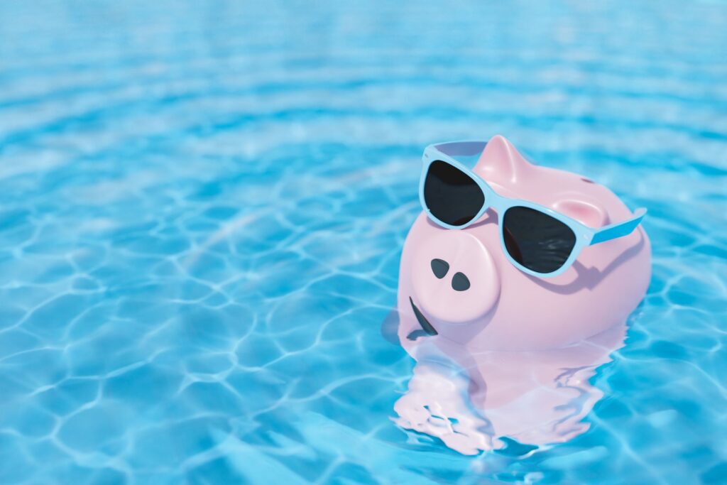 Sparschwein mit Sonnenbrille schwimmt im Pool