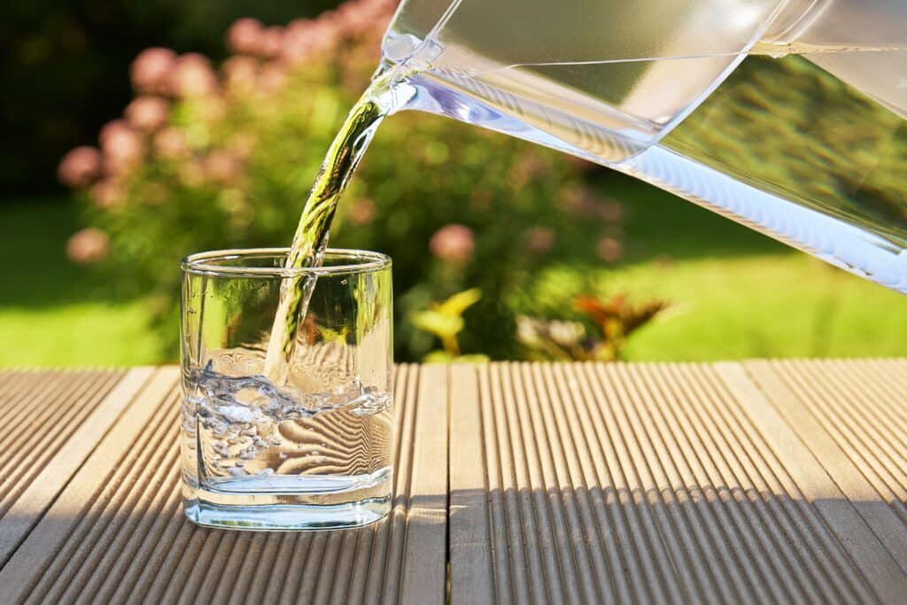 Jemand gießt sich ein Glas Wasser ein