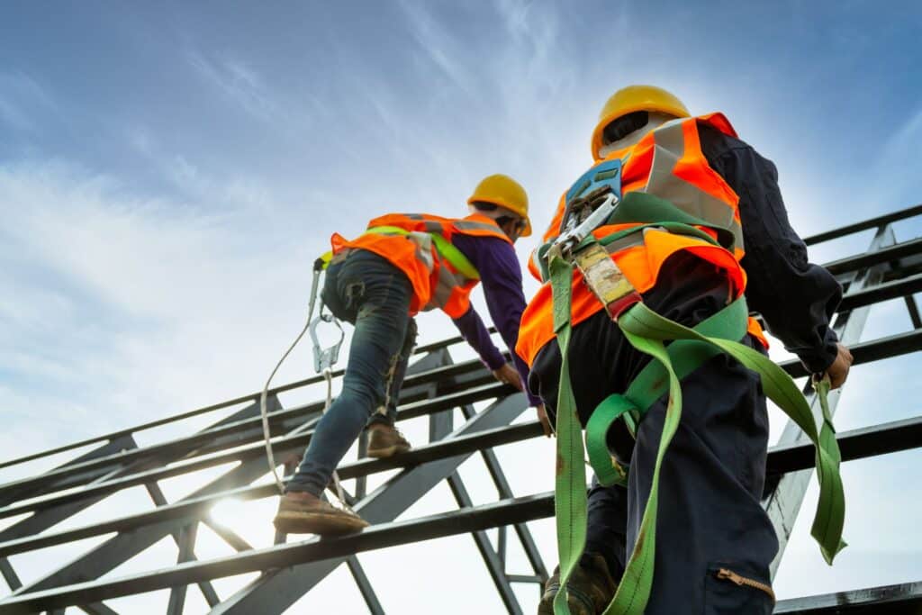 Zwei Arbeiter mit Sicherheitsgurten bei Arbeiten auf einem Gerüst