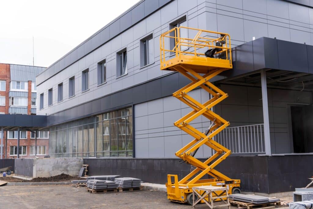 Scherenarbeitsbühne vor einer modernen Fassade auf einer Baustelle