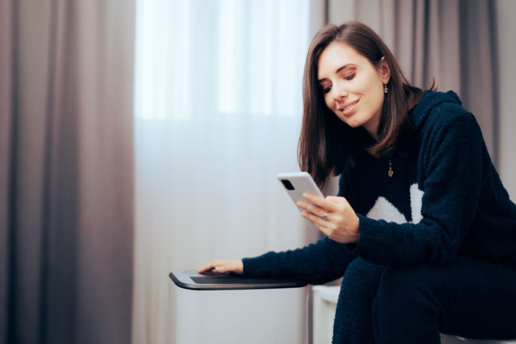 oung woman in comfortable clothing looking at her smartphone while seated indoors